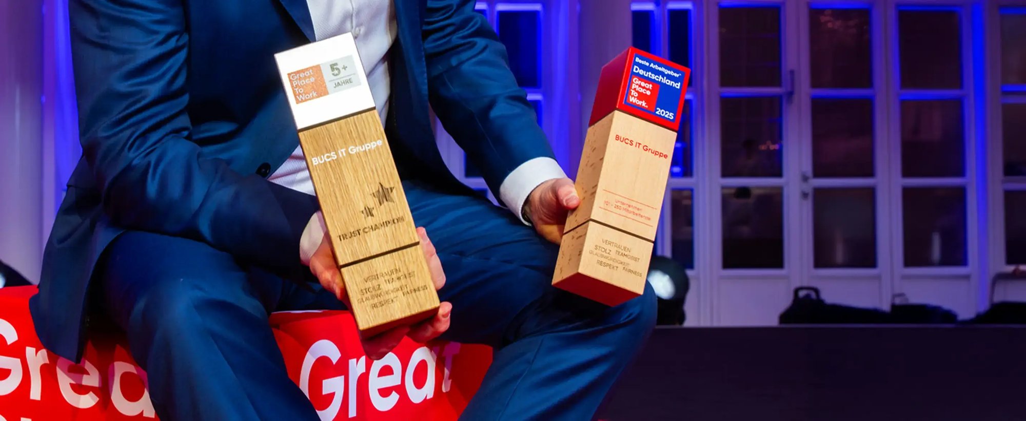 Ein Mann hält die Auszeichnung zum Great Pleace to Work 2025 in den Händen.