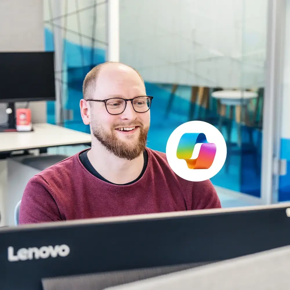 Ein Nutzer von Copilot Microsoft M 365 sitzt vor zwei Monitoren