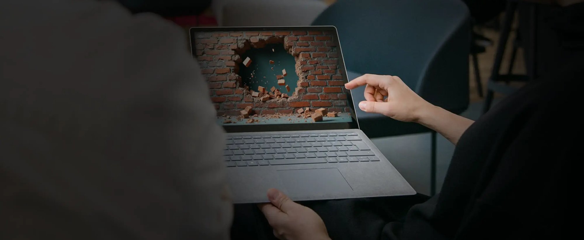 Ein Laptop mit einer löchrigen Mauer als Symbolbild für eine veraltete Firewall