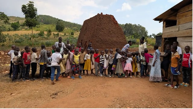 Schüler einer Schule in Uganda stehen vor einer Baustelle