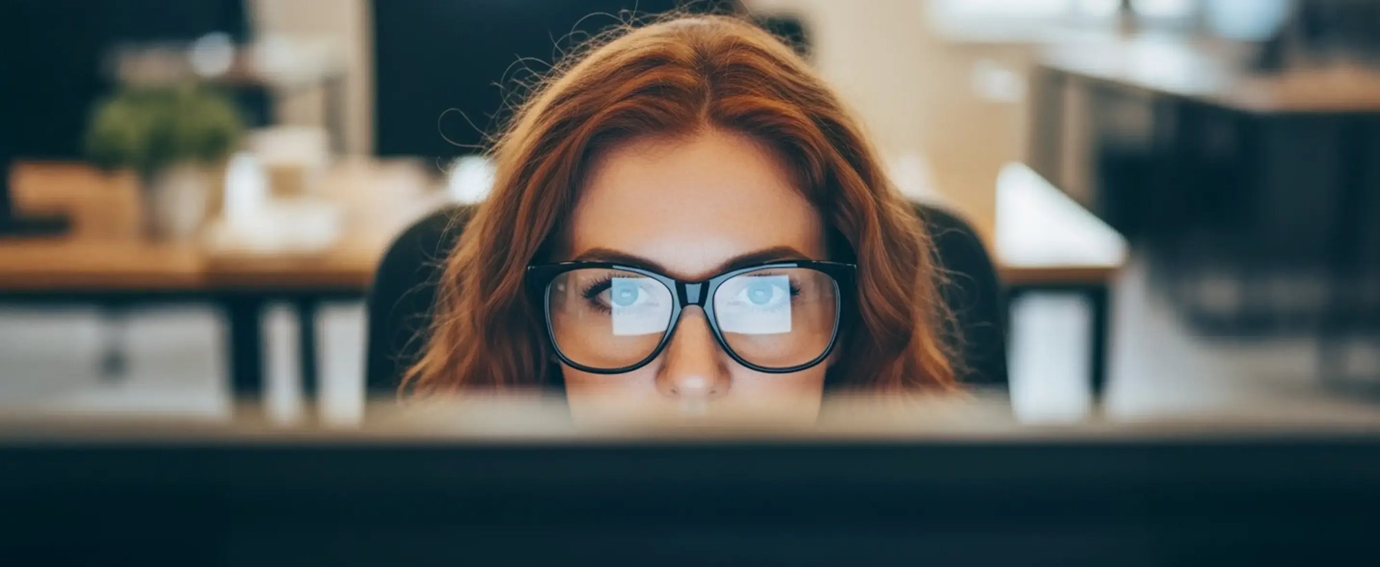 Eine Frau sitzt in einem Büro und monitort einen Evil-VM-Angriff (KI-generiert)