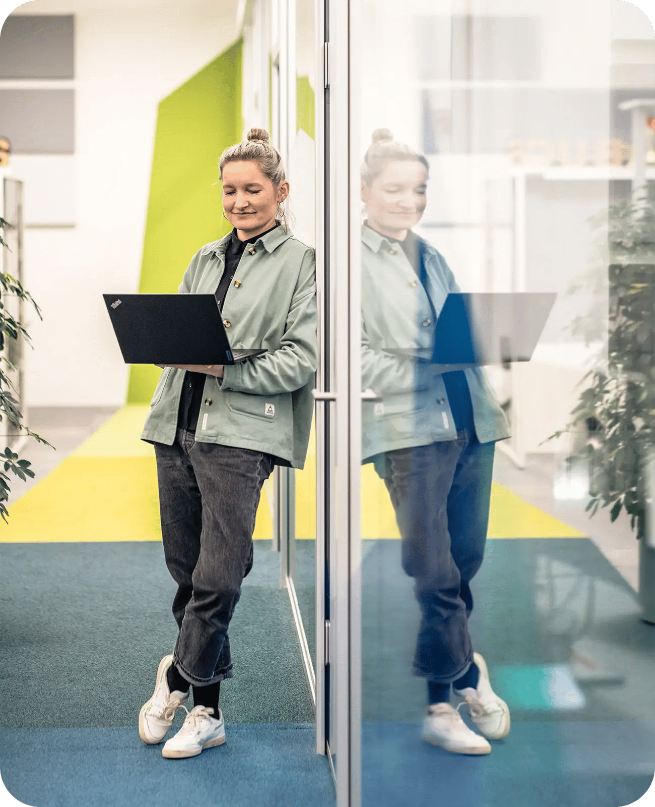 Eine Frau steht vor einer Glaswand und prüft die Netzwerksegmentierung mit ihrem Laptop