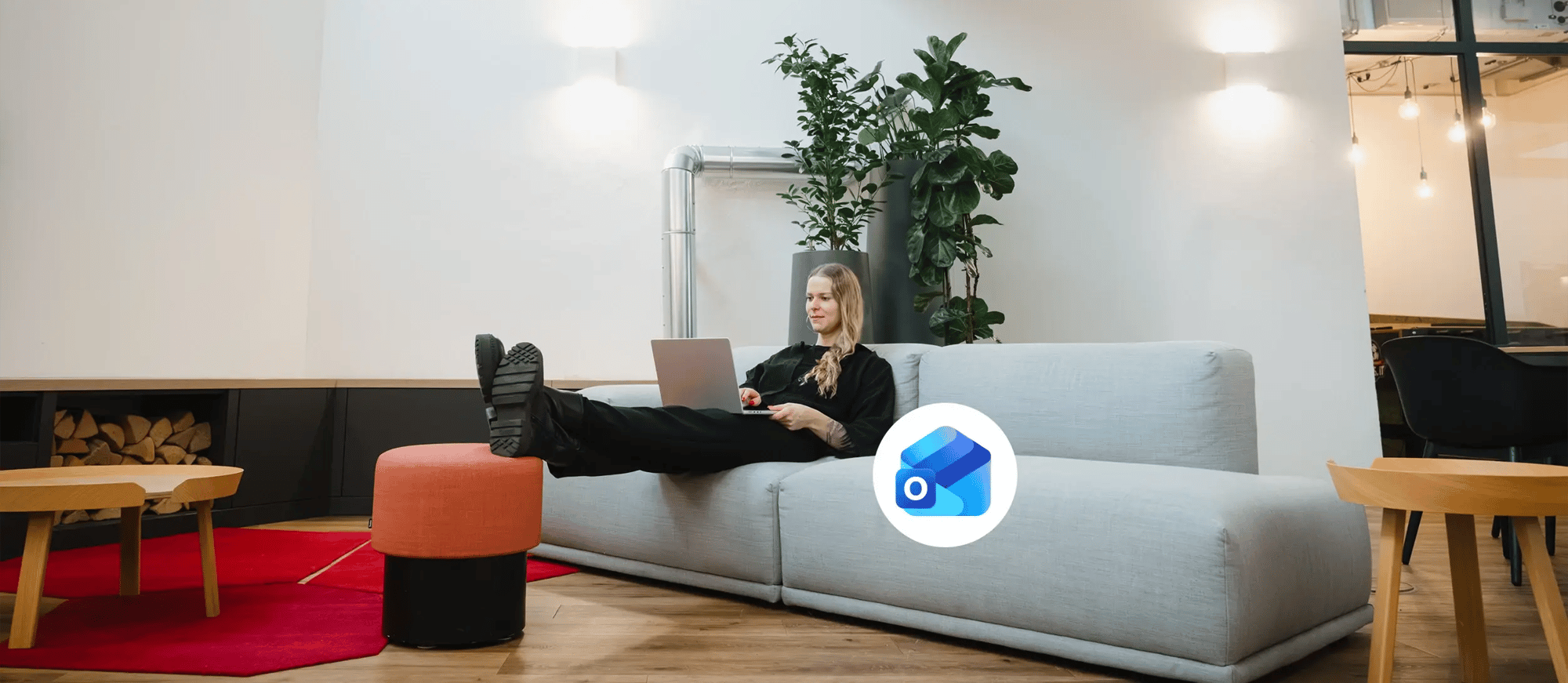 Eine junge Frau sitzt mit einem Laptop auf einer Couch