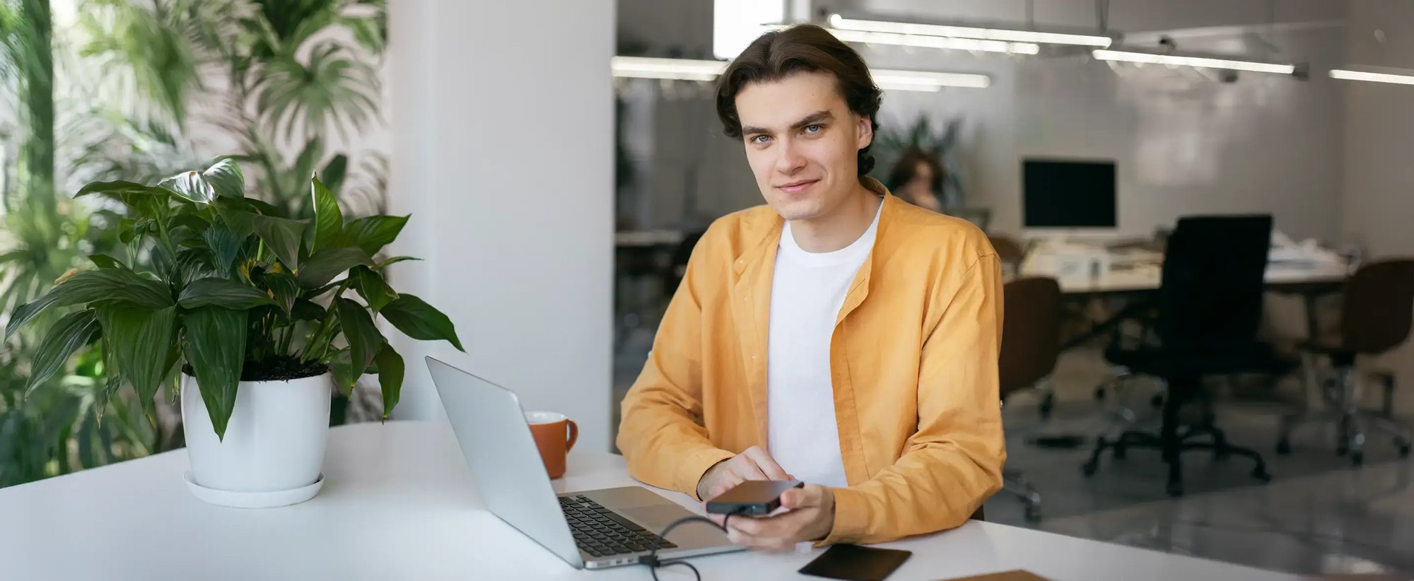Ein Mann sitzt entspannt vor einem Laptop und benutzt den USB-Anschluss