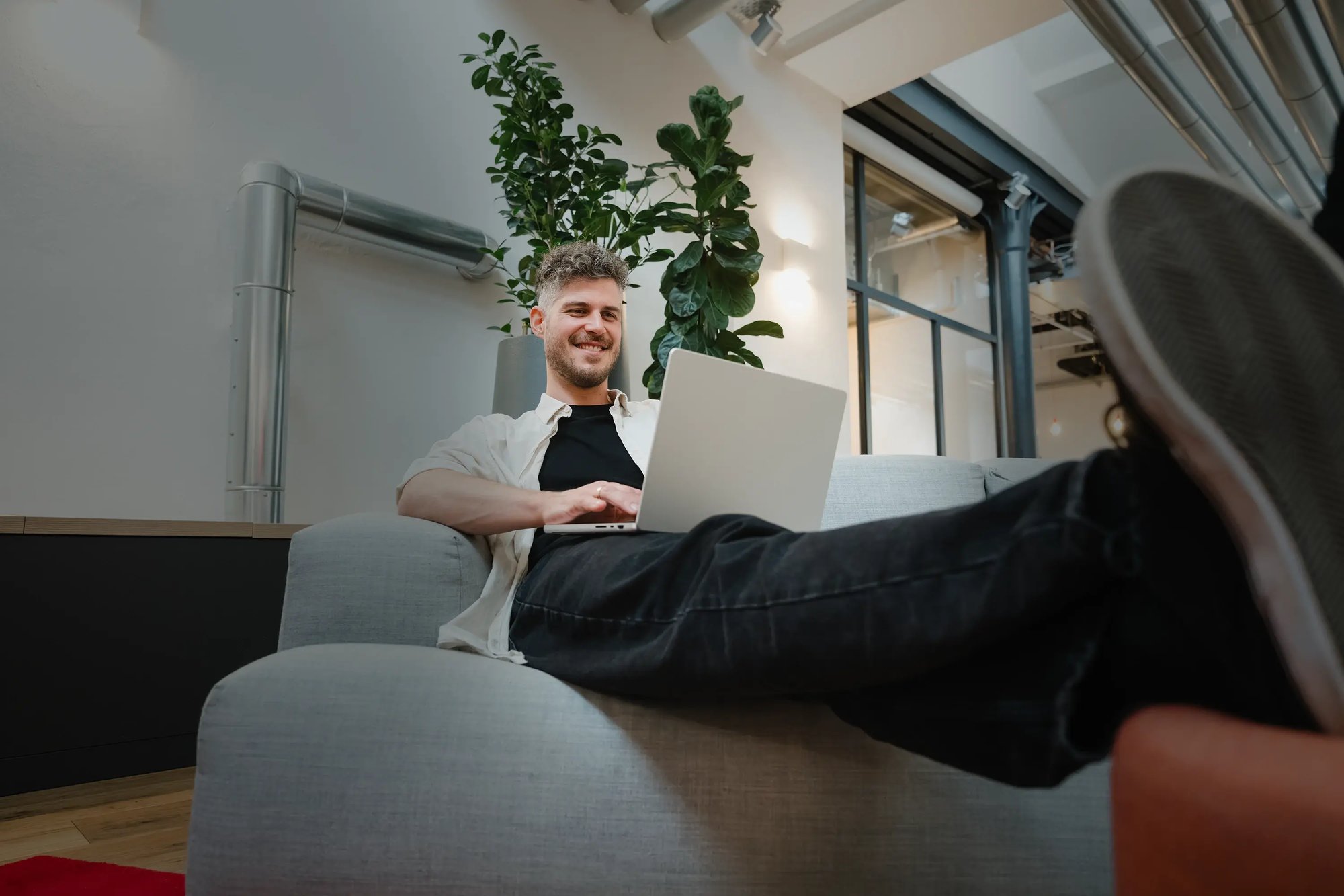 Ein Mann arbeitet mit einem Laptop von einer Couch aus