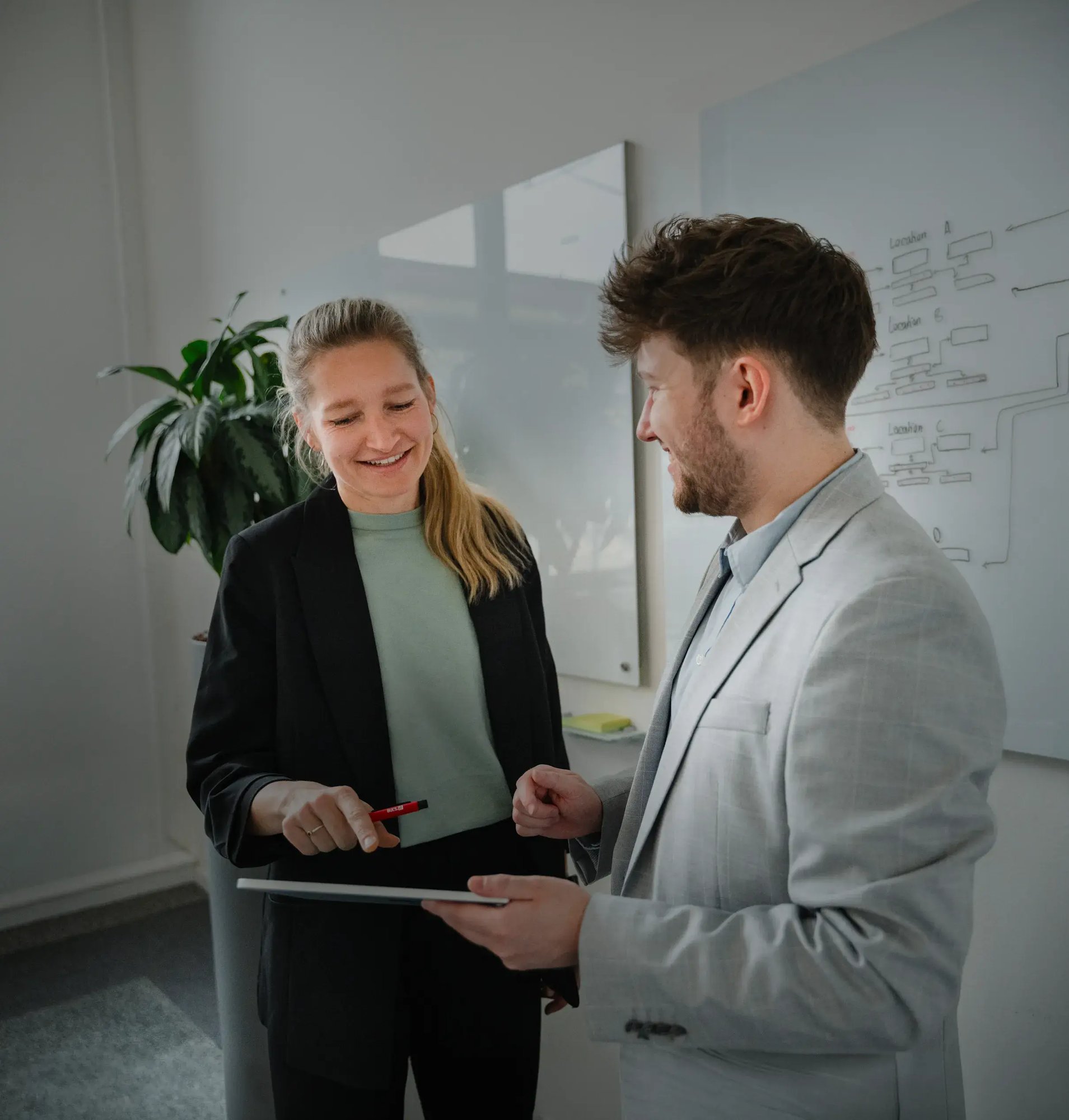 Zwei Menschen schauen gemeinsam auf einen Laptop in einem hellen Büro.