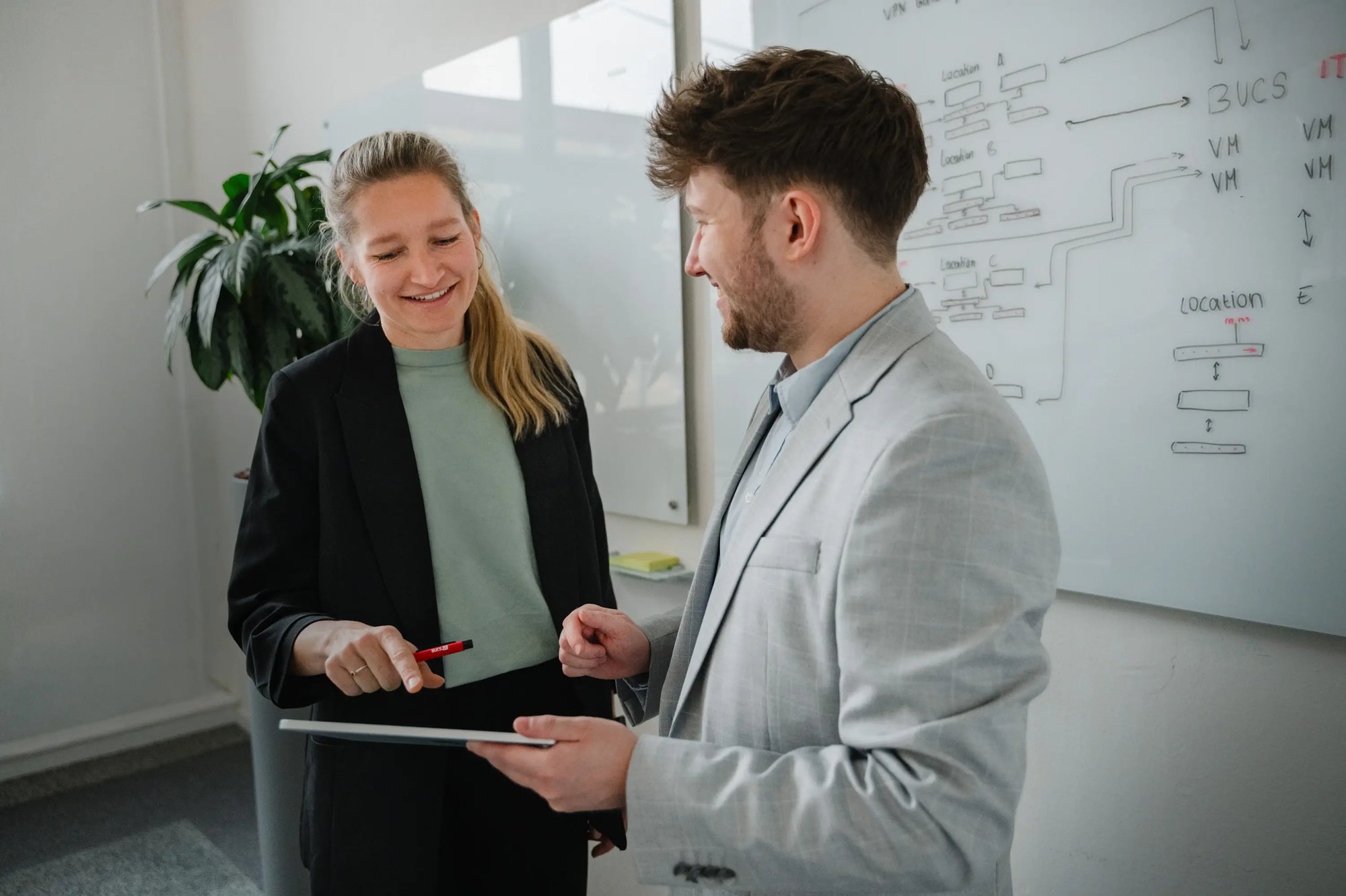 Zwei Menschen schauen gemeinsam auf einen Laptop in einem hellen Büro.
