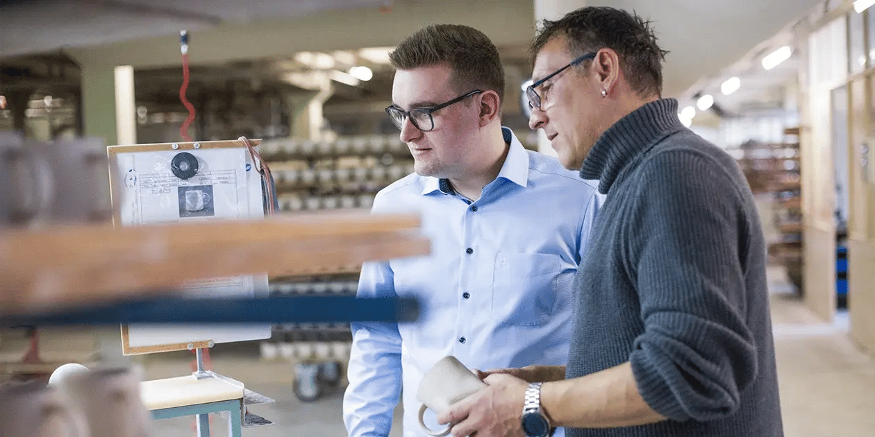 Ein IT-Berater besichtigt die Hallen und spricht mit einem Mitarbeiter