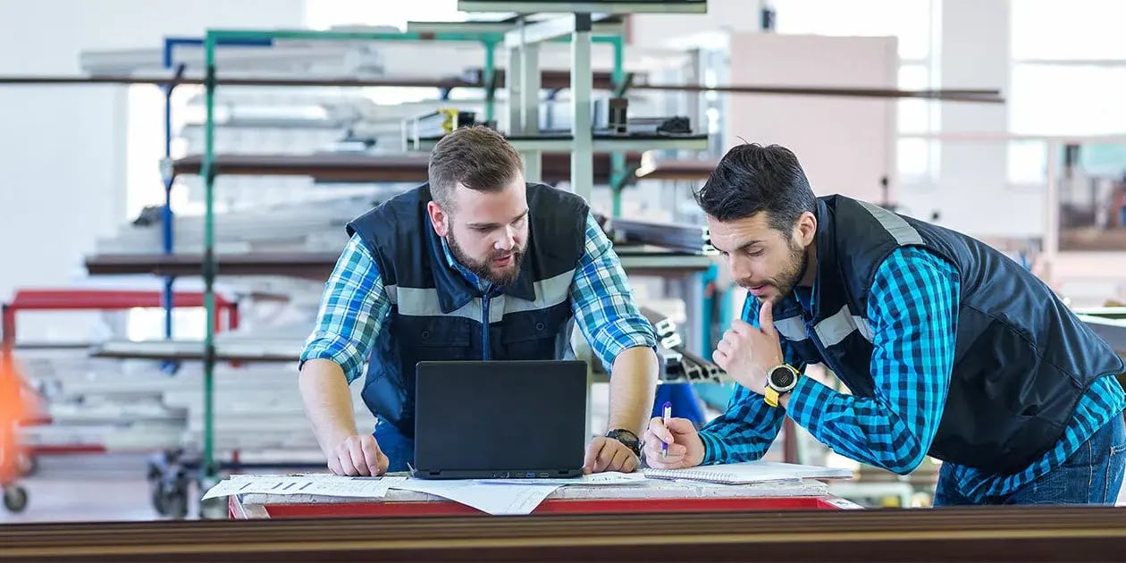 Zwei Mitarbeiter arbeiten an einem Tisch in einer Halle