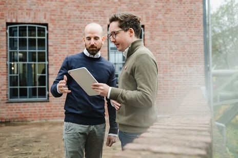 Ein IT-Experte berät sich mit einem Kunden vor einer Hauswand