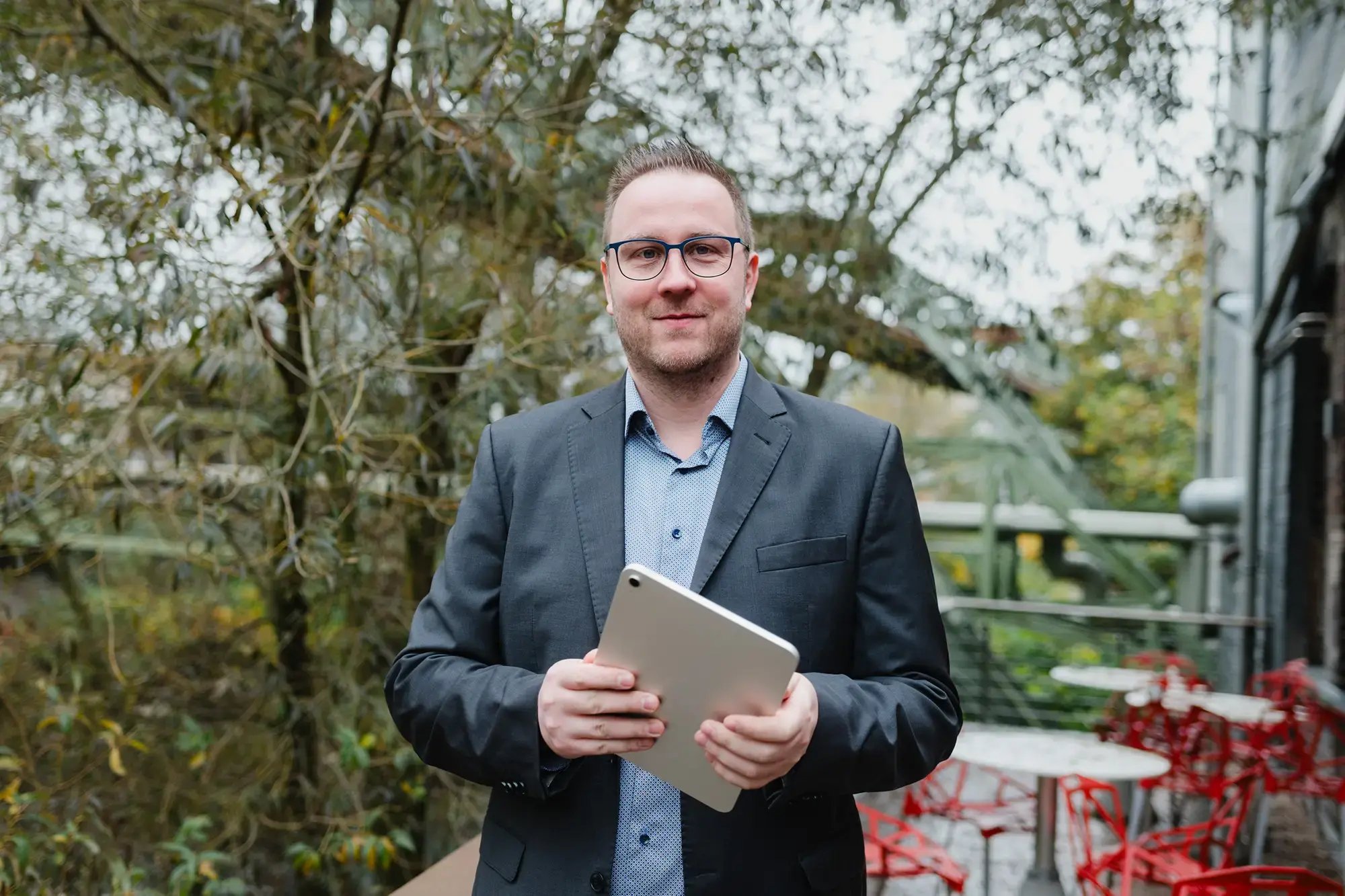 Ein freundlicher Mann mit Tablet und blauem Anzug