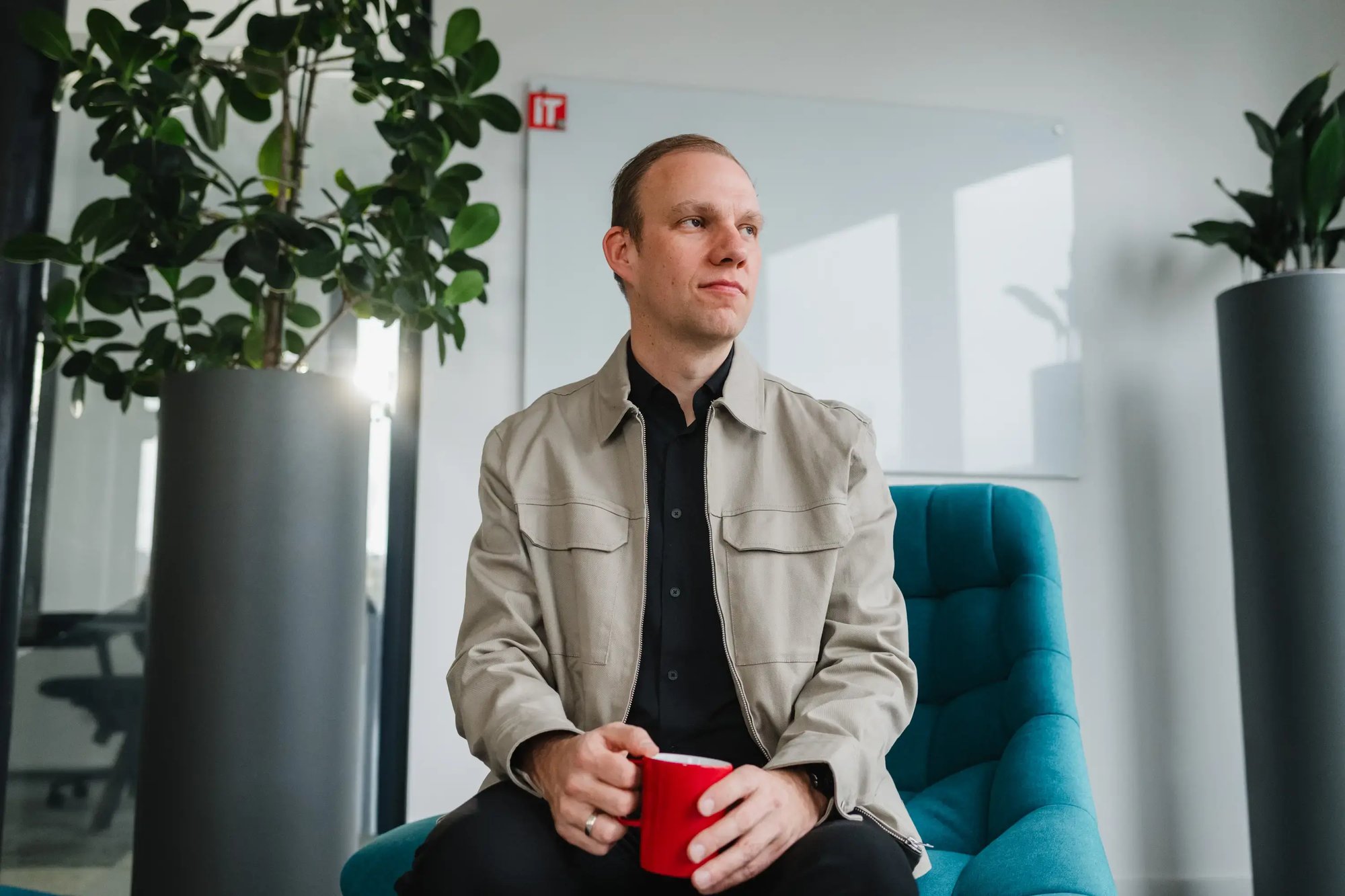 Ein IT-Experte auf einem Sessel hält eine rote Tasse