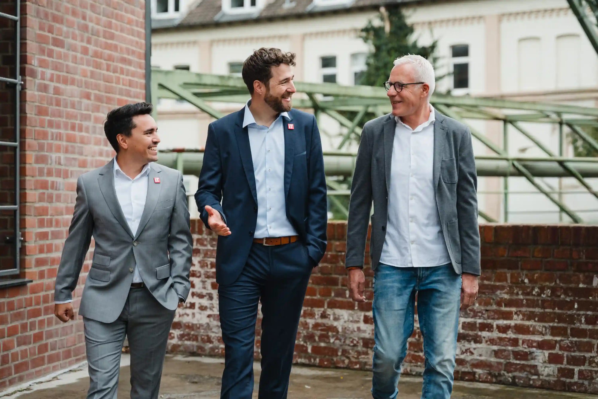 Drei Männer gehen gemeinsam eine Straße herunter und unterhalten sich